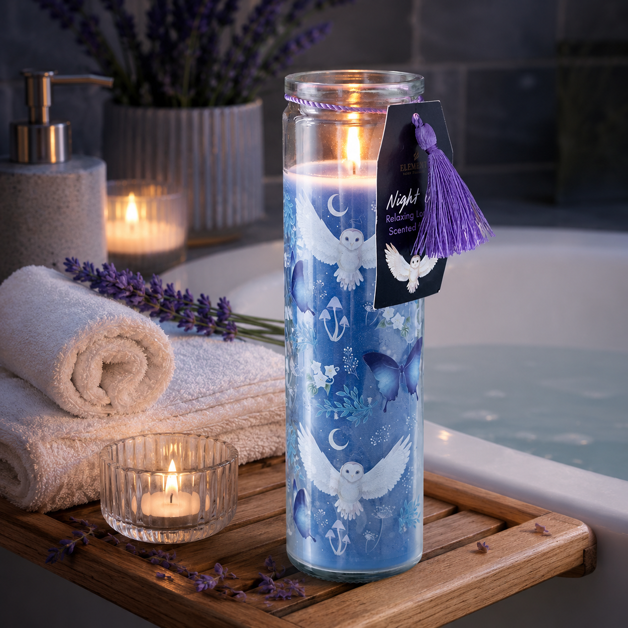Decorative candle with owl design on a wooden tray near towels and a bathtub.